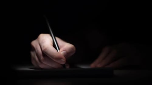 Man Writing Ideas While Working on Laptop