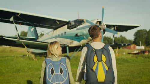 Enamored Couple Walking Toward Airplane on Green Field