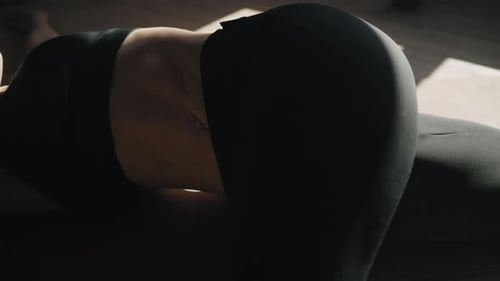 Slender Woman In Black Sportswear Lying On Floor And Doing Physical Exercise For Body Beauty