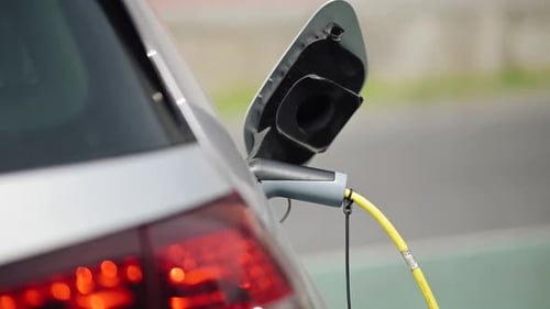 Eine Nahaufnahme eines Ladeadapters, der an ein graues Elektrofahrzeug angeschlossen ist, mit einer Detailansicht