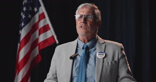 Man Speaks at Podium with American Flag