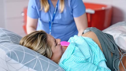 Femme blonde souffrant de douleurs lors des contractions. La ceinture de cardiotocographie est attachée au gros ventre