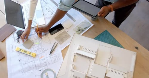 Arbeit an Architekturplänen, Person mit Tablet und Stift am Schreibtisch