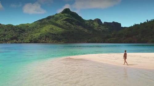 Woman Walking on a White Sand Beach with Lush Green Mountains Maupiti French Polynesia