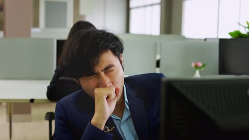 Asian man employee is tired from working hard in the office