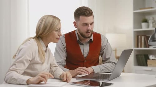 Colleagues Discussing Work on Laptop in Office