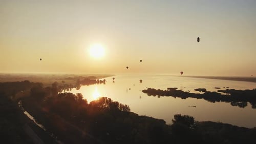 Stunning 4K aerial footage of a drone filming hot air balloons. Flying over farming fields and river