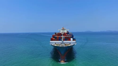 Aerial front view tracking of a very large container cargo ship traveling