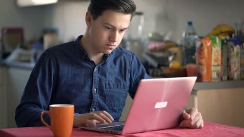 Un adolescent utilise un ordinateur portable de manière détendue et navigue sur Internet à la maison