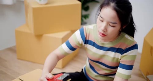 Young woman closes a box that has already been packed.