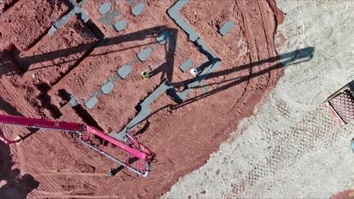 House Foundation is Being Filled with Wet Concrete By Builder Using a Concrete Pump