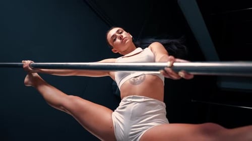 vídeo vertical Chica flexible haciendo ejercicios de gimnasia en un poste para estirarse Hermosa mujer sexy