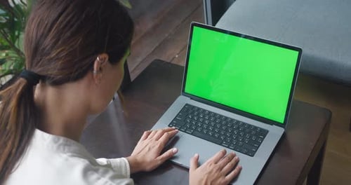 Over the Shoulder Shot Young Woman is Working on Computer with a Mockup Green Screen