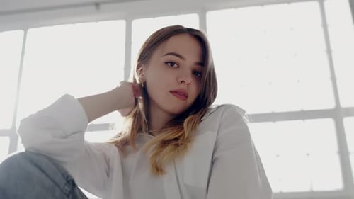 Young Woman in White Shirt Posing Thoughtfully By Window