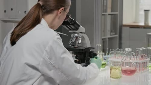 Woman Scientist Works with Microscope in Laboratory