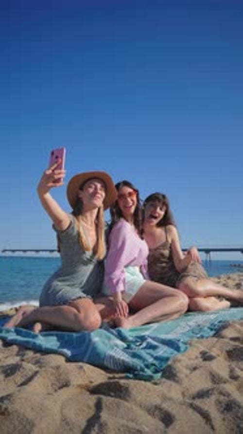Vertical Three Dressed Women Lying on the Sand of the Beach Taking a Selfie Portrait with a