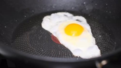 Ein Ei in einer Pfanne kochen, Spiegelei kochen (Vertikales Video)