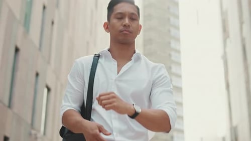 Young businessman looking at his wristwatch while standing in the business district