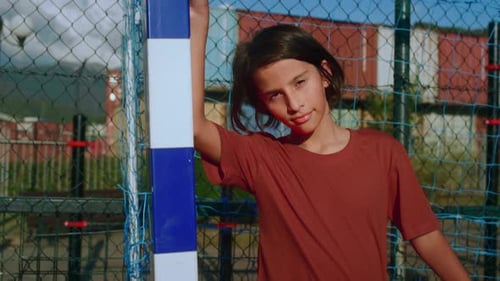 Young Goalkeeper of School Sports Team Leans Tiredly on Goalpost After Match Closeup