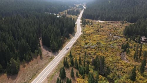 Aerial View of a Lonely Car on Road in Rural Countryside Valley in Autumn Colors Surrounded With Gre