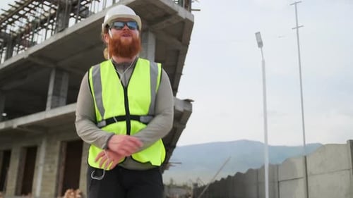 Joyful charismatic civil engineer with red beard in sunglasses dancing to music on headphones relaxi