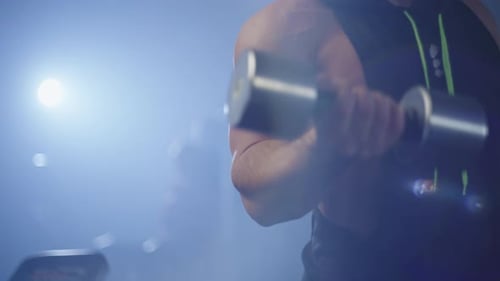 Muscular Man Bicep Curls with Dumbbell in Gym