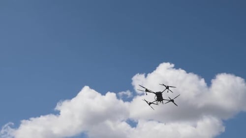Drone Flies Through Blue Sky with Clouds