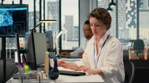 Workers Typing at Computers in Modern City Office