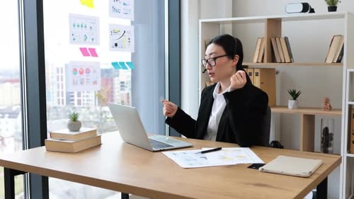 Asian Businesswoman in Headset Making Online Video Call in Office