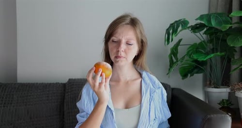 Woman Frowning While Holding Orange Indoors Expressing Dislike Food