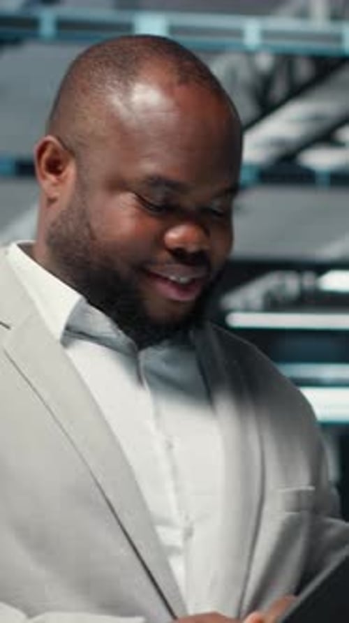 Vertical Video Happy Engineer Walking in Data Center Refining Algorithms on Tablet