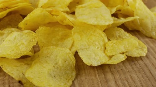 Kartoffelchips rotieren aus nächster Nähe auf einem Holzbrett.
