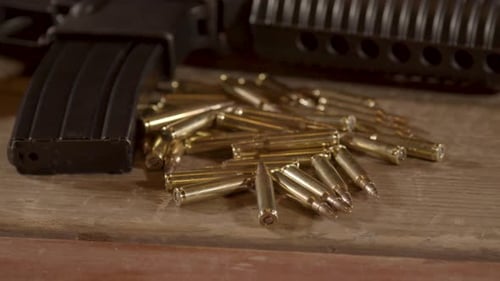 Close dolly out of a lot of ammunition lying in front of AR-15 rifle