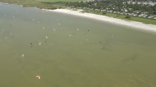 Aerial view of people doing kite surfing along the beach sunny day, Netherlands