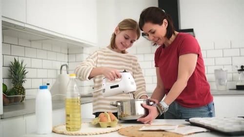 Mother and Teen Daughter Baking Together in Kitchen