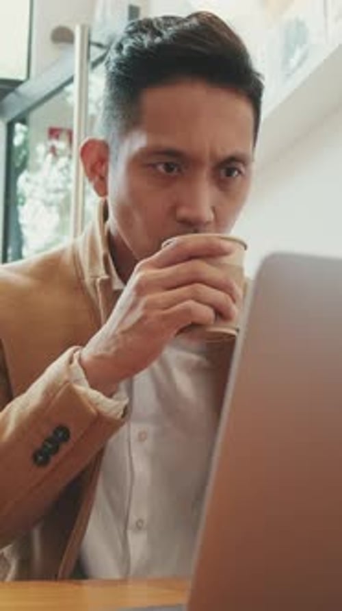 Young Man Working on Laptop in Cafe