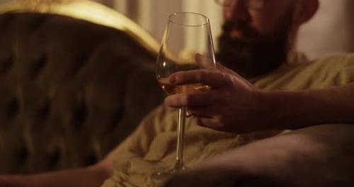 Man Relaxes on Couch with Glass of Drink