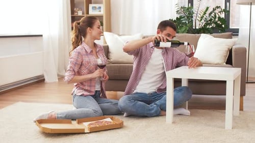 Couple Pours Wine and Eats Pizza Together at Home
