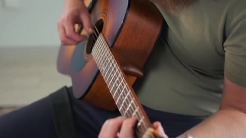 Long-Haired Adult Plays Acoustic Guitar Indoors