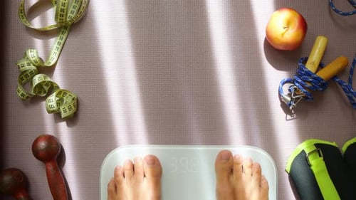 Feet stepping onto scale on yoga mat