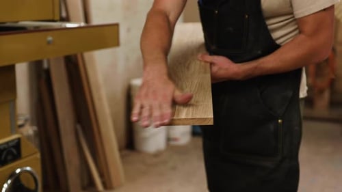 Skilled carpenter checking wood piece for smoothness in workshop during daytime
