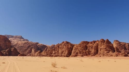 Pan across Wadi Rum river valley vista with bright blue sky in the desert