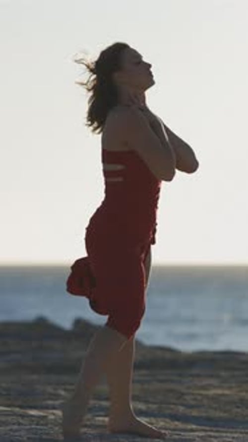 Woman in Red Dress Dancing on Ocean Beach