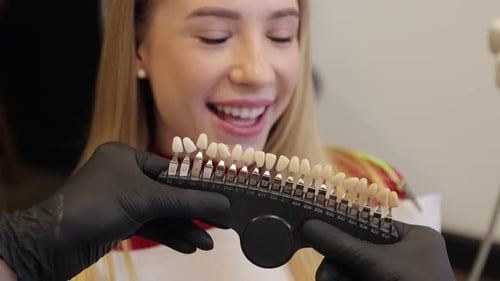 Woman Smiles as Teeth Shades Compared in Office