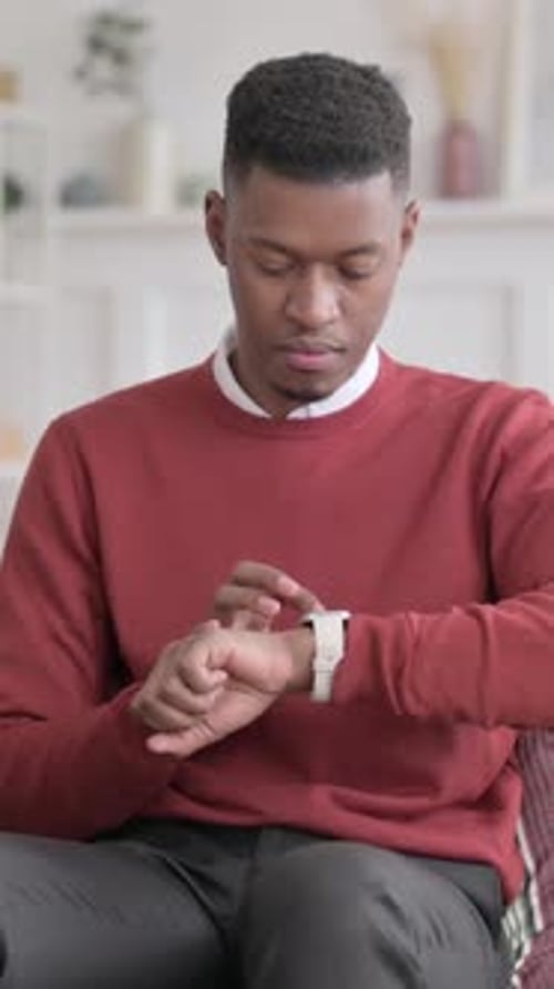 African Man using Smart Watch while Sitting on Sofa, Vertical Video