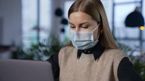 Woman with Mask Typing on Laptop Indoors
