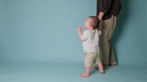 Happy toddler baby learns to walk and takes his first steps with the help mother