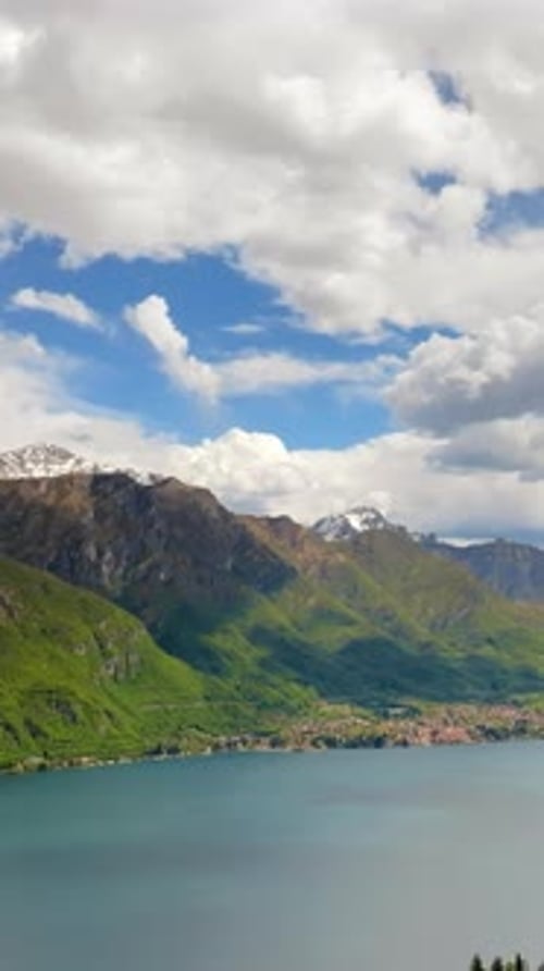 Lateral aerial drone panorama of Lake Como surrounded by mountains in Italy. Vertical