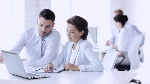 Business team collaborating on laptop in office setting