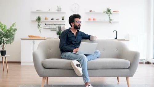 Person mit Kaffee, die zu Hause über einen tragbaren Computer bloggt